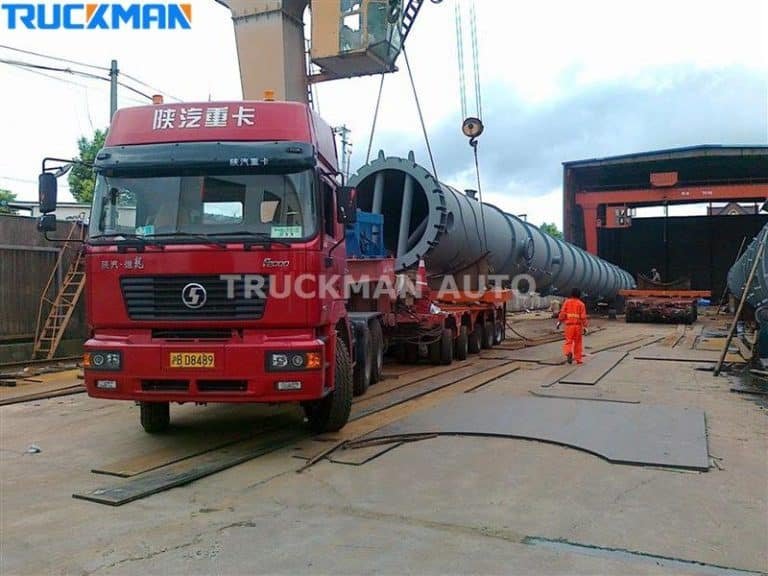 Low bed semi-trailer carrying yellow wheel loader and bulldozer