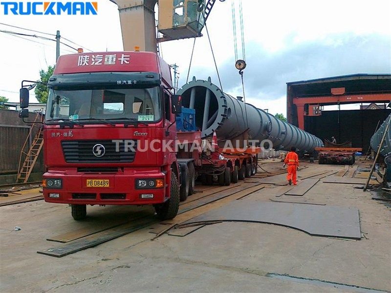 Low bed semi-trailer carrying yellow wheel loader and bulldozer
