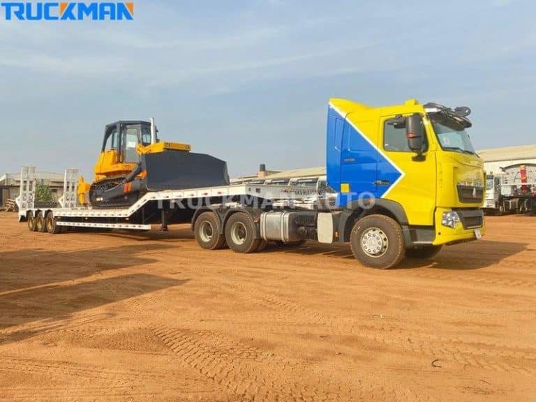 Construction machinery being prepared for transport on a low rider semi-trailer