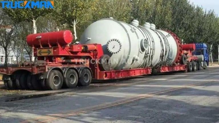 Heavy load transport with a low bed semi-trailer carrying large industrial tanks