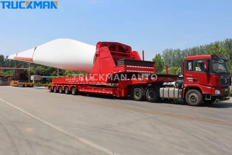 Low-bed semi-trailer loaded with long white wind turbine blades, powerful heavy-duty capacity