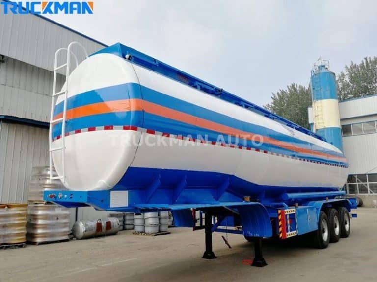 A colourful striped fuel tanker parked in an industrial area surrounded by industrial equipment