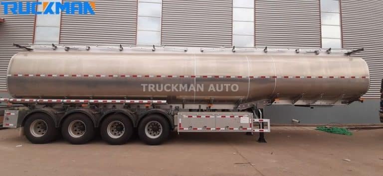 Long side view of a shiny, empty fuel tanker trailer in Truckman Auto's parking area