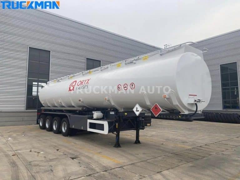 Stationary white Oryx Energies chemical tanker trailer with hazard placards at Truckman Auto depot