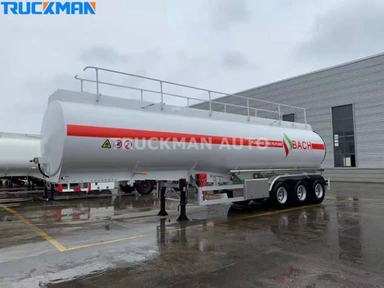 Modernized white fuel tanker with Dangerous Goods logo, parked on the wet surface of an industrial estate.