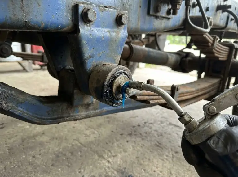 Fresh blue grease purging from truck suspension zerk fitting